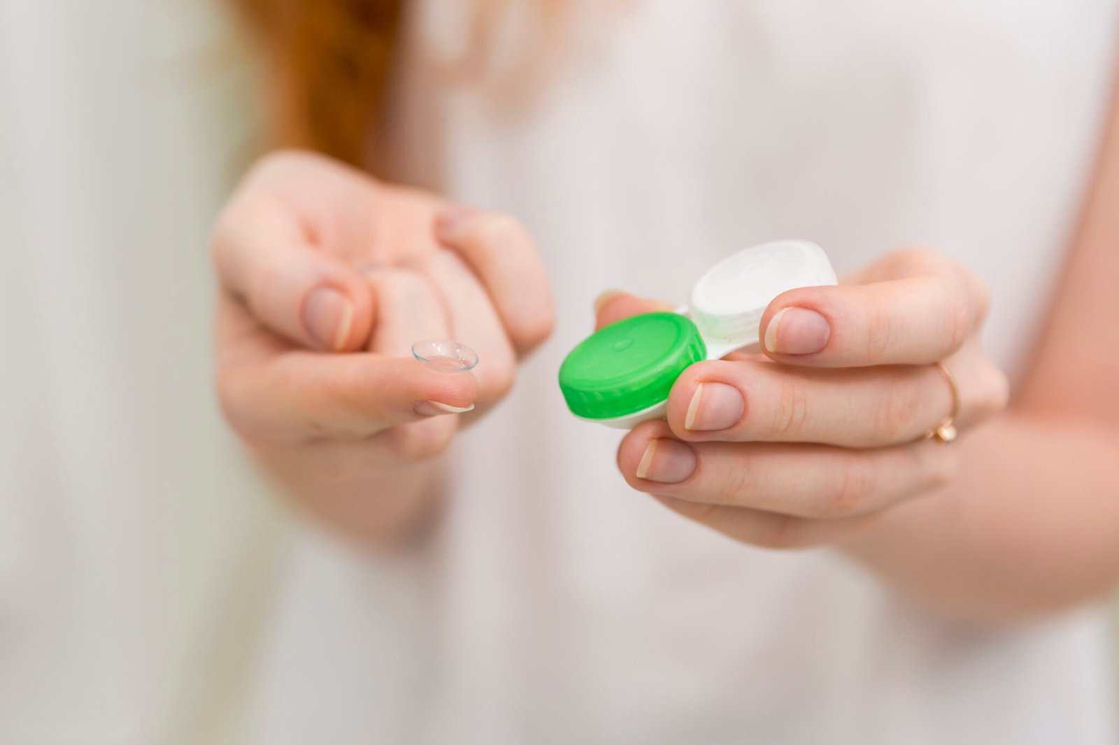 close up of woman hand holding contact lens and it s container scaled